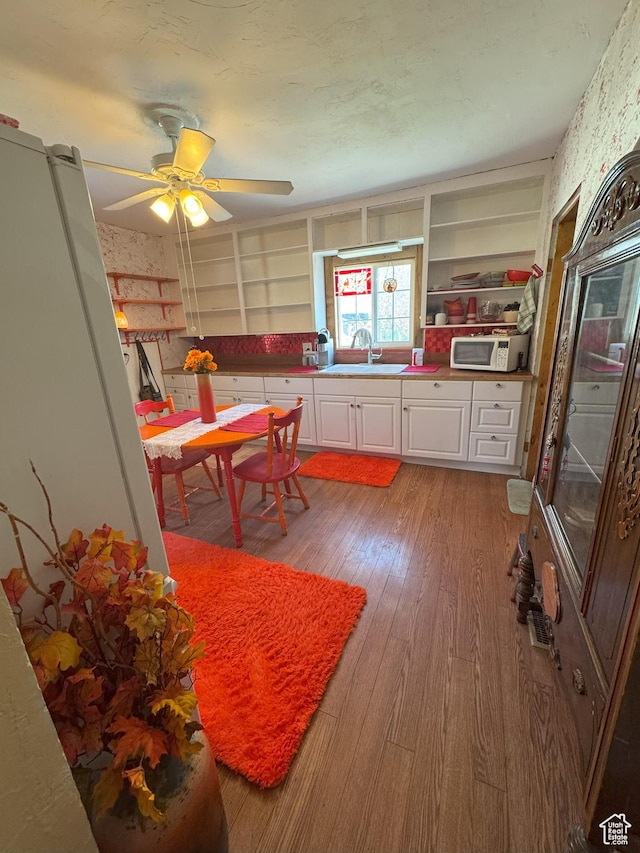 kitchen featuring white cabinets, open shelves, a sink, and light wood finished floors