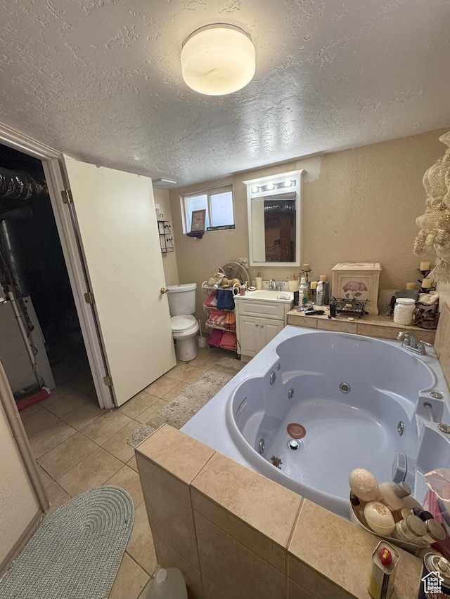 full bath featuring tile patterned floors, a whirlpool tub, toilet, vanity, and a textured ceiling