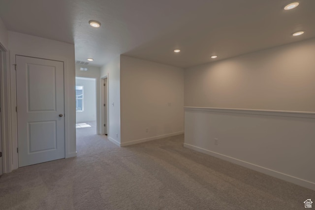 spare room with light carpet, recessed lighting, and baseboards