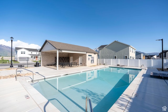 community pool featuring fence, a patio, and a residential view