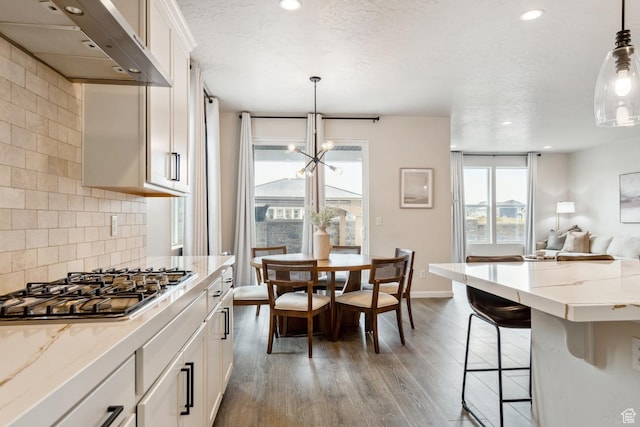 kitchen with light stone counters, stainless steel gas stovetop, open floor plan, light wood finished floors, and ventilation hood