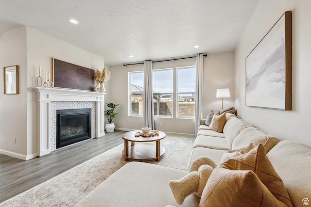 living room with recessed lighting, wood finished floors, a tiled fireplace, and baseboards