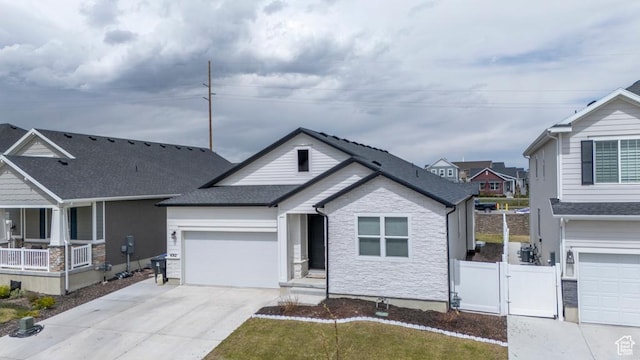 single story home with a gate, fence, driveway, stone siding, and a garage