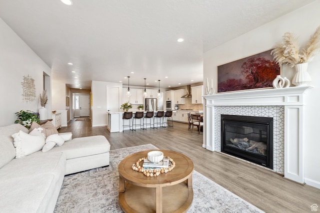 living area with light wood-style flooring, baseboards, recessed lighting, and a fireplace