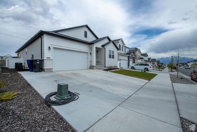 view of front facade featuring concrete driveway, an attached garage, a residential view, and cooling unit