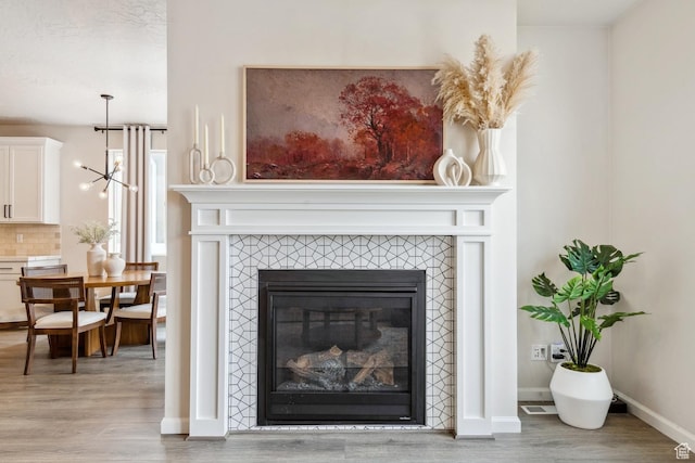 room details with wood finished floors, visible vents, baseboards, decorative backsplash, and a fireplace