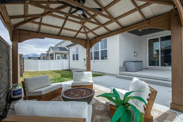 view of patio / terrace featuring a gazebo, a ceiling fan, a fenced backyard, and an outdoor living space