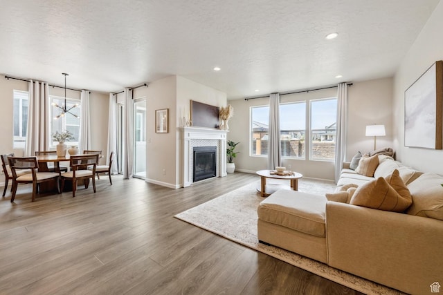 living room featuring a textured ceiling, light wood-type flooring, a wealth of natural light, and a tile fireplace