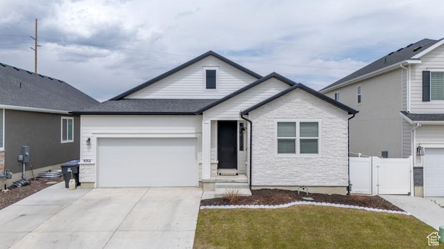 view of front of home with a gate, fence, concrete driveway, stone siding, and a garage