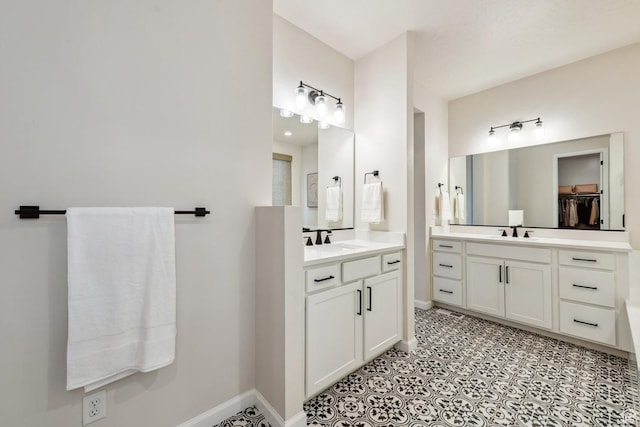 full bathroom featuring two vanities, baseboards, and a sink