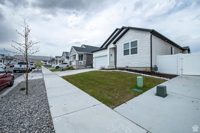 single story home featuring a gate, a residential view, driveway, a front yard, and a garage