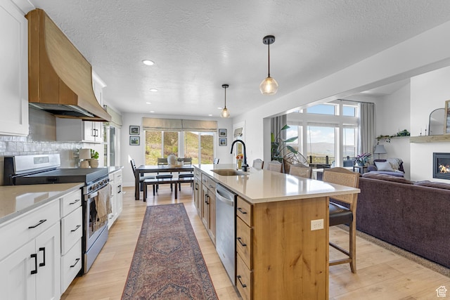 86 Elk Ridge Dr W, Elk Ridge, UT 84651 - kitchen with stainless steel appliances, a sink, a breakfast bar area, a glass covered fireplace, and open floor plan