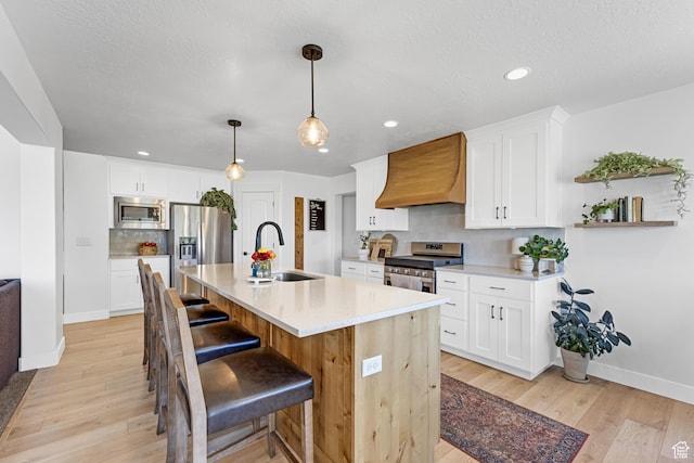 86 Elk Ridge Dr W, Elk Ridge, UT 84651 - kitchen with appliances with stainless steel finishes, a sink, premium range hood, baseboards, and light wood-style flooring