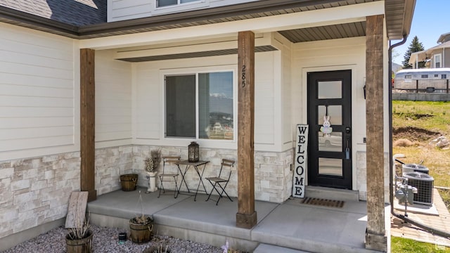 285 W Olympic Ln, Elk Ridge, UT 84651 - entrance to property featuring stone siding, a shingled roof, covered porch, and central AC