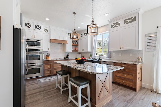 285 W Olympic Ln, Elk Ridge, UT 84651 - kitchen featuring light wood-type flooring, stainless steel appliances, a center island, and tasteful backsplash