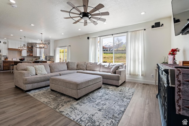 285 W Olympic Ln, Elk Ridge, UT 84651 - living room with a textured ceiling, light wood-type flooring, baseboards, recessed lighting, and ceiling fan with notable chandelier
