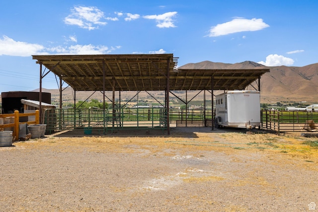 view of parking featuring a detached carport, a mountain view, and an exterior structure