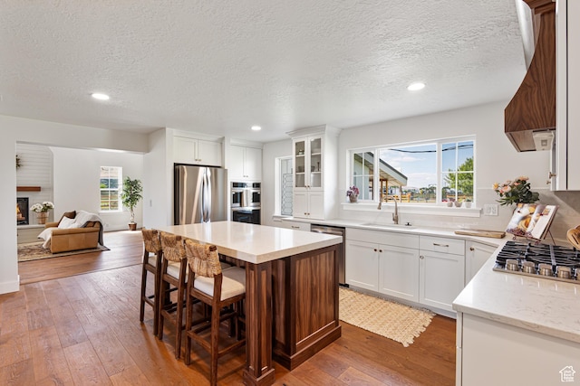5186 W 9970 S, Payson, UT 84651 - kitchen with appliances with stainless steel finishes, a sink, hardwood / wood-style floors, a kitchen island, and a kitchen breakfast bar