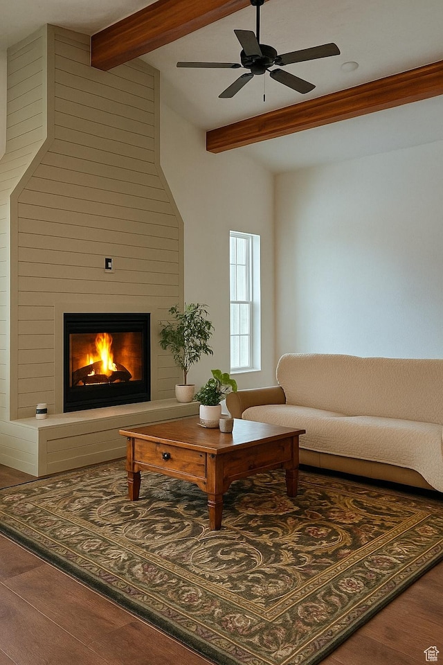 living room featuring wood finished floors, ceiling fan, beam ceiling, and a large fireplace