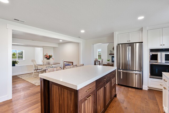 5186 W 9970 S, Payson, UT 84651 - kitchen with appliances with stainless steel finishes, hardwood / wood-style flooring, white cabinetry, a kitchen island, and recessed lighting