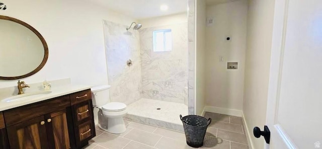 bathroom with vanity, tile patterned flooring, toilet, and tiled shower