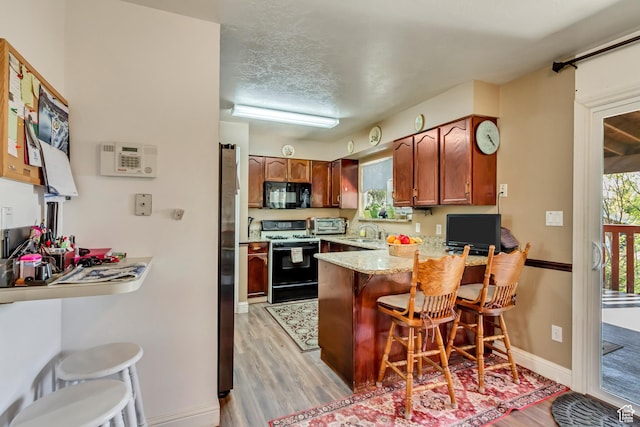 572 S Main St, Kaysville, UT 84037 - kitchen with a peninsula, a sink, light wood-type flooring, gas range, and black microwave