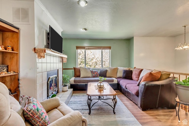 572 S Main St, Kaysville, UT 84037 - living room with a textured ceiling, wood finished floors, a chandelier, a fireplace, and visible vents