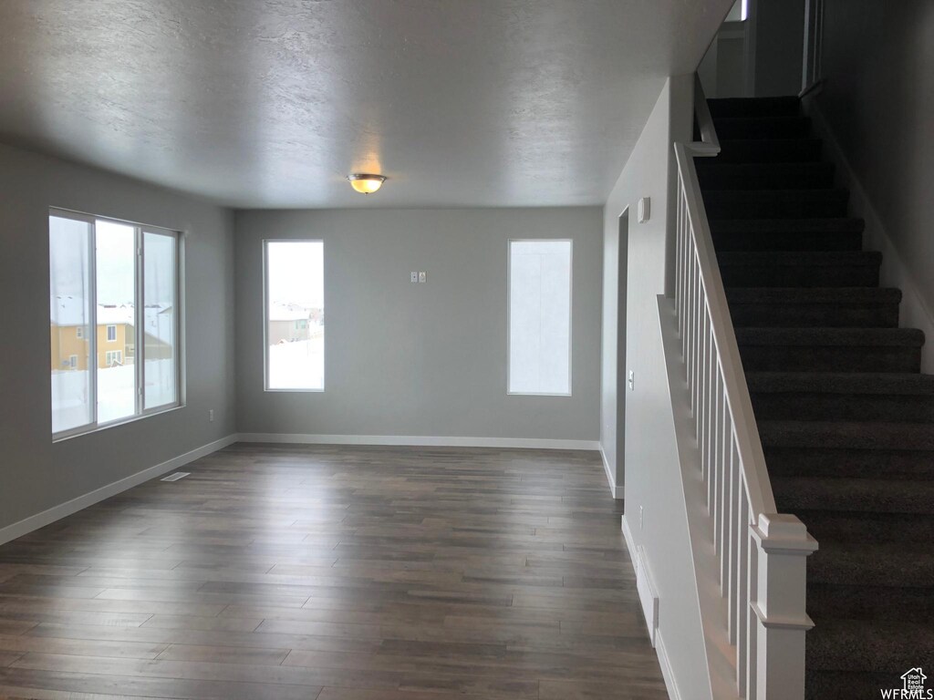 312 W Sapphire Dr, Tooele, UT 84074 - unfurnished living room featuring baseboards, dark wood-style flooring, and stairs