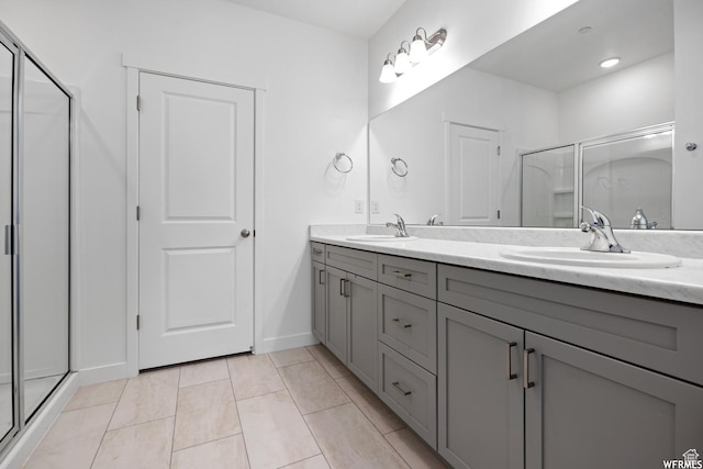 full bathroom featuring baseboards, a sink, a shower stall, and double vanity