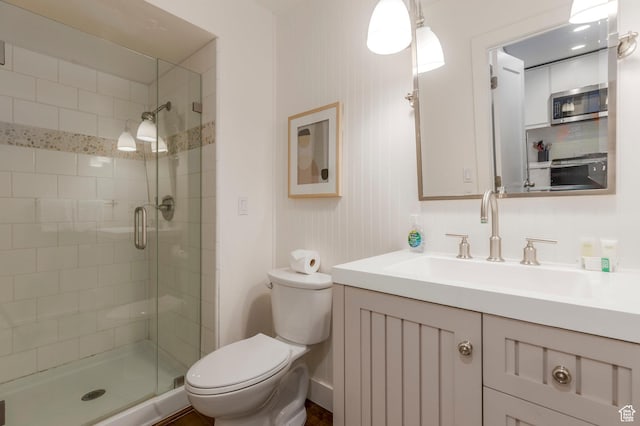 bathroom featuring toilet, vanity, and a stall shower
