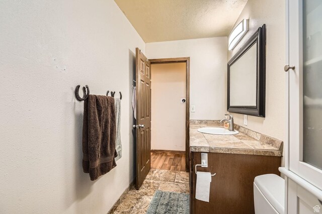 115 S 200 E, Cedar Fort, UT 84013 - bathroom featuring stone finish floor, toilet, vanity, baseboards, and a textured ceiling
