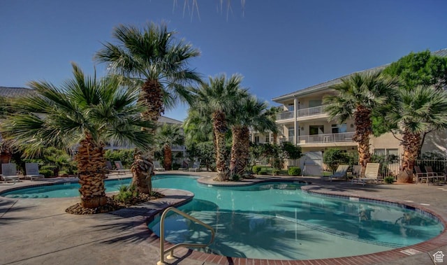 community pool with a patio and fence