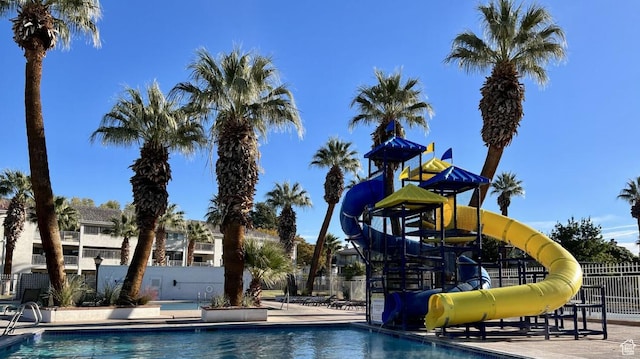 community pool featuring a water slide, fence, and playground community