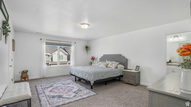 bedroom featuring ensuite bath, baseboards, and light carpet