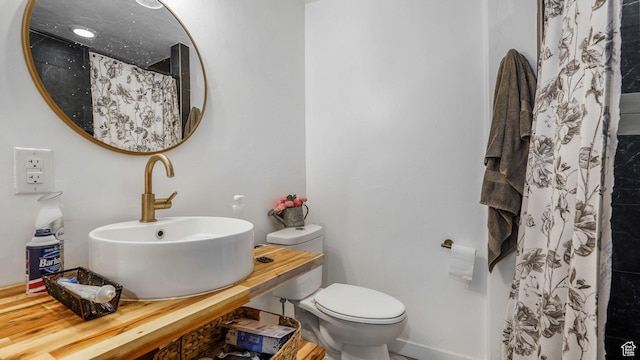 full bathroom with baseboards, a shower with curtain, a sink, and toilet