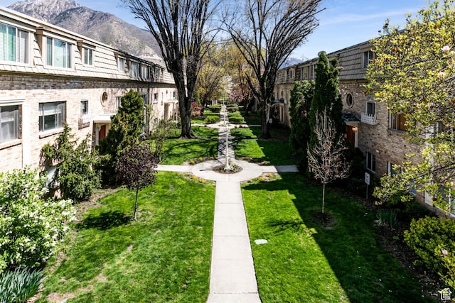 view of property's community featuring a lawn and a mountain view
