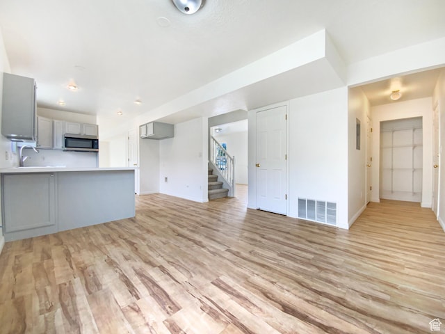 654 W 100 N, Spanish Fork, UT 84660 - unfurnished living room featuring stairway, visible vents, a sink, light wood-style floors, and baseboards