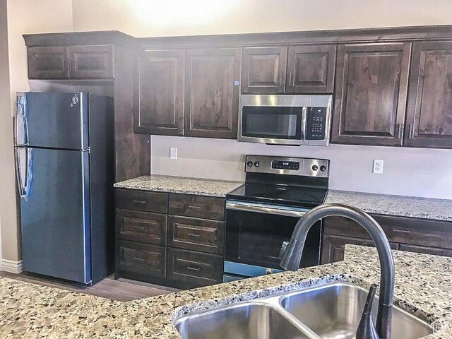 232 W 200 S, Ivins, UT 84738 - kitchen with dark brown cabinets, light stone countertops, a sink, and appliances with stainless steel finishes