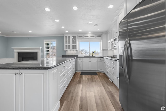 kitchen with stainless steel appliances, wood finished floors, recessed lighting, and white cabinetry