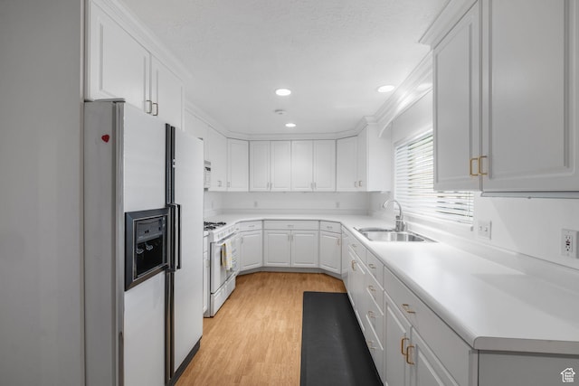 kitchen featuring white cabinets, recessed lighting, a sink, white appliances, and light wood-type flooring