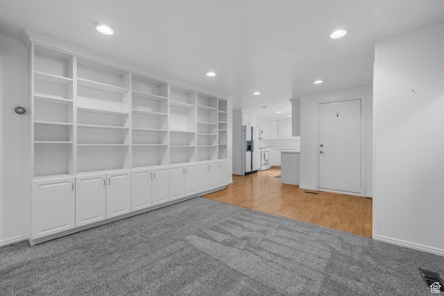unfurnished living room with recessed lighting, light wood-type flooring, visible vents, and light carpet