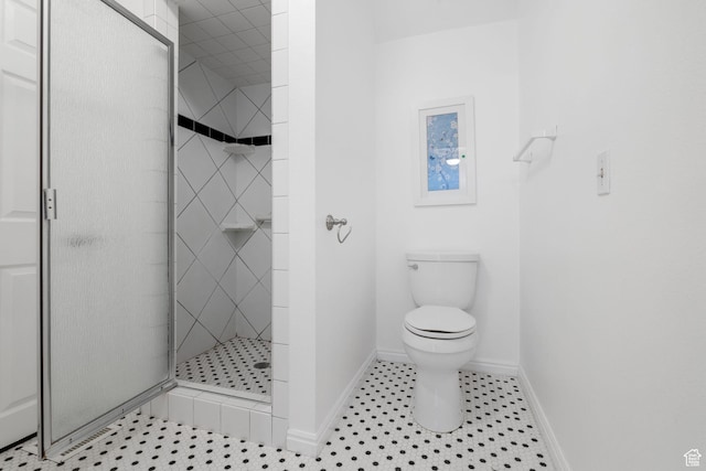 bathroom featuring baseboards, a shower stall, and toilet