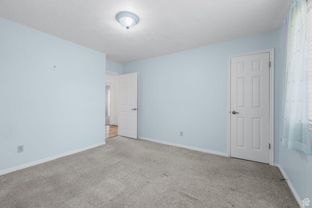 carpeted spare room with baseboards and a textured ceiling