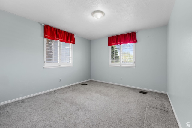 unfurnished room featuring carpet floors, visible vents, and baseboards