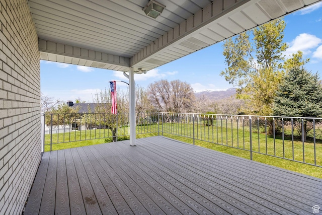 wooden deck featuring a fenced backyard, a mountain view, and a yard