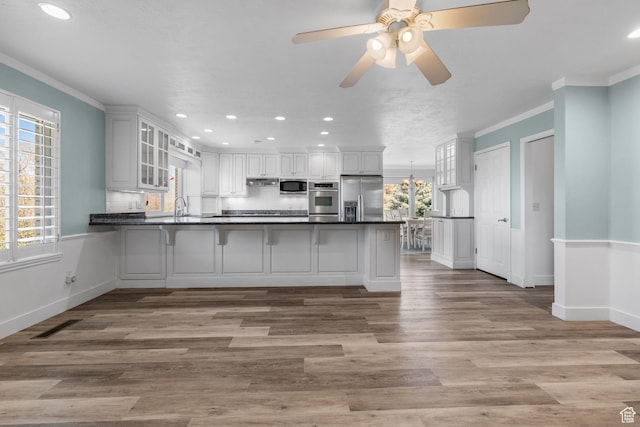 kitchen with recessed lighting, stainless steel appliances, dark countertops, a peninsula, and glass insert cabinets