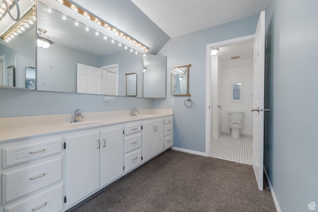 bathroom featuring double vanity, toilet, baseboards, and a sink