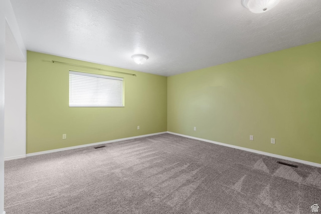 unfurnished room with carpet floors, a textured ceiling, baseboards, and visible vents