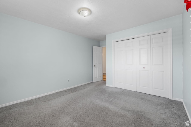unfurnished bedroom with baseboards, carpet floors, and a closet