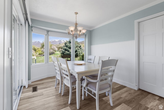 dining room with visible vents, light wood finished floors, a wainscoted wall, and an inviting chandelier
